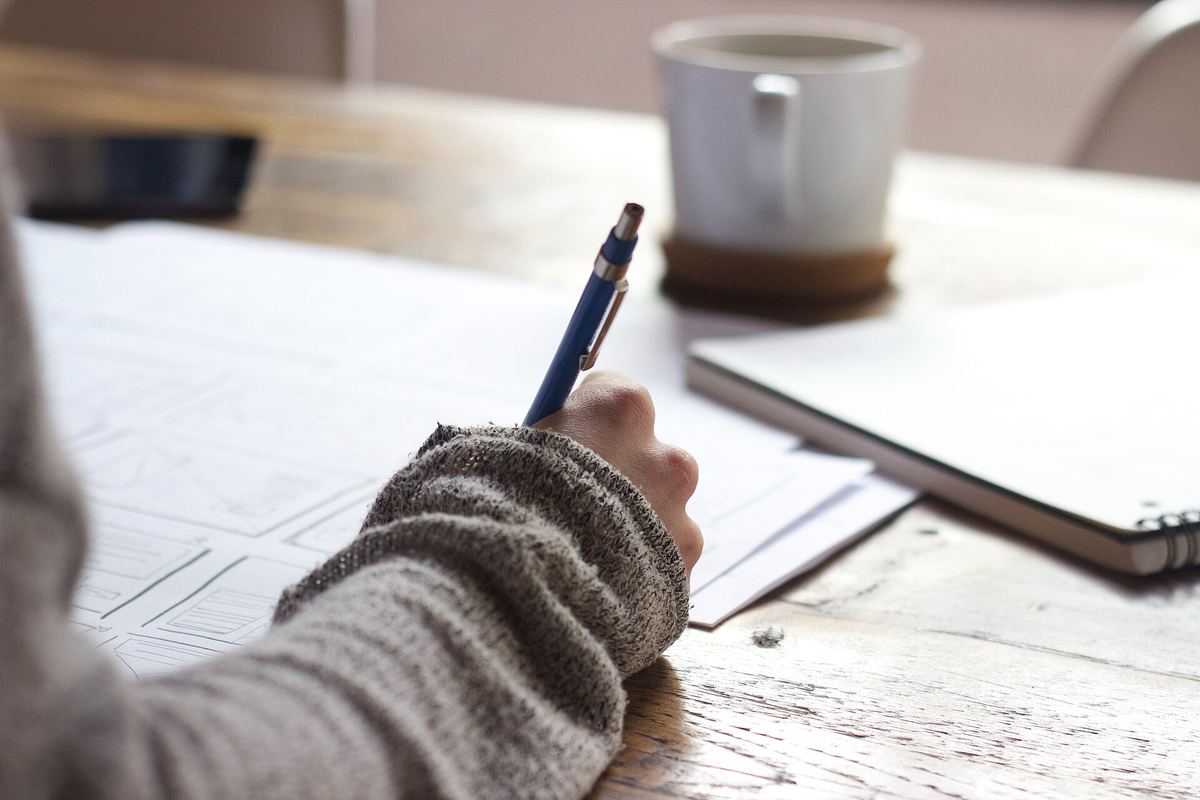 Hand mit Stift, die Notizen auf einem Blatt Papier macht